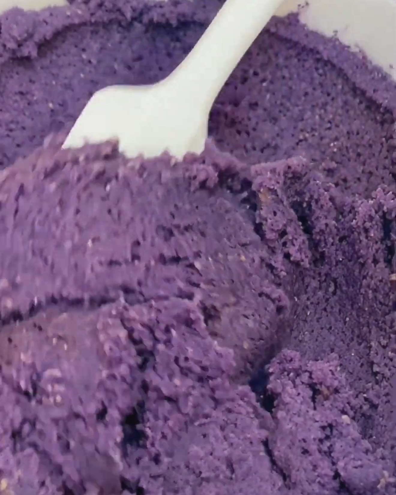Pâte à cookie ube violette intense pliée avec une spatule blanche après l'ajout de poudre d'ube UBE NOLIA®