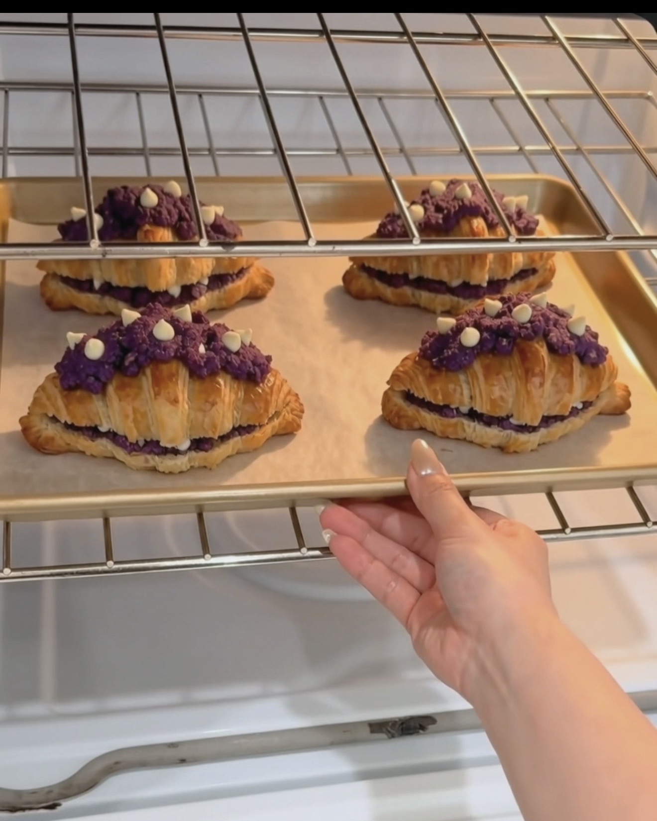 Plaque de crookies à l'ube UBE NOLIA® fraîchement sortis du four avec des couches de croissant dorées et une garniture de cookie à l'ube (igname violette) violette avec des pépites de chocolat blanc
