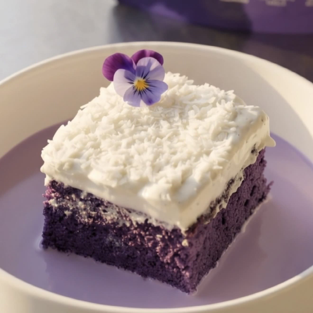 Part de gâteau tres leches à l'ube coco nappée de chantilly coco et noix de coco râpée, prête à déguster | Ube Nolia