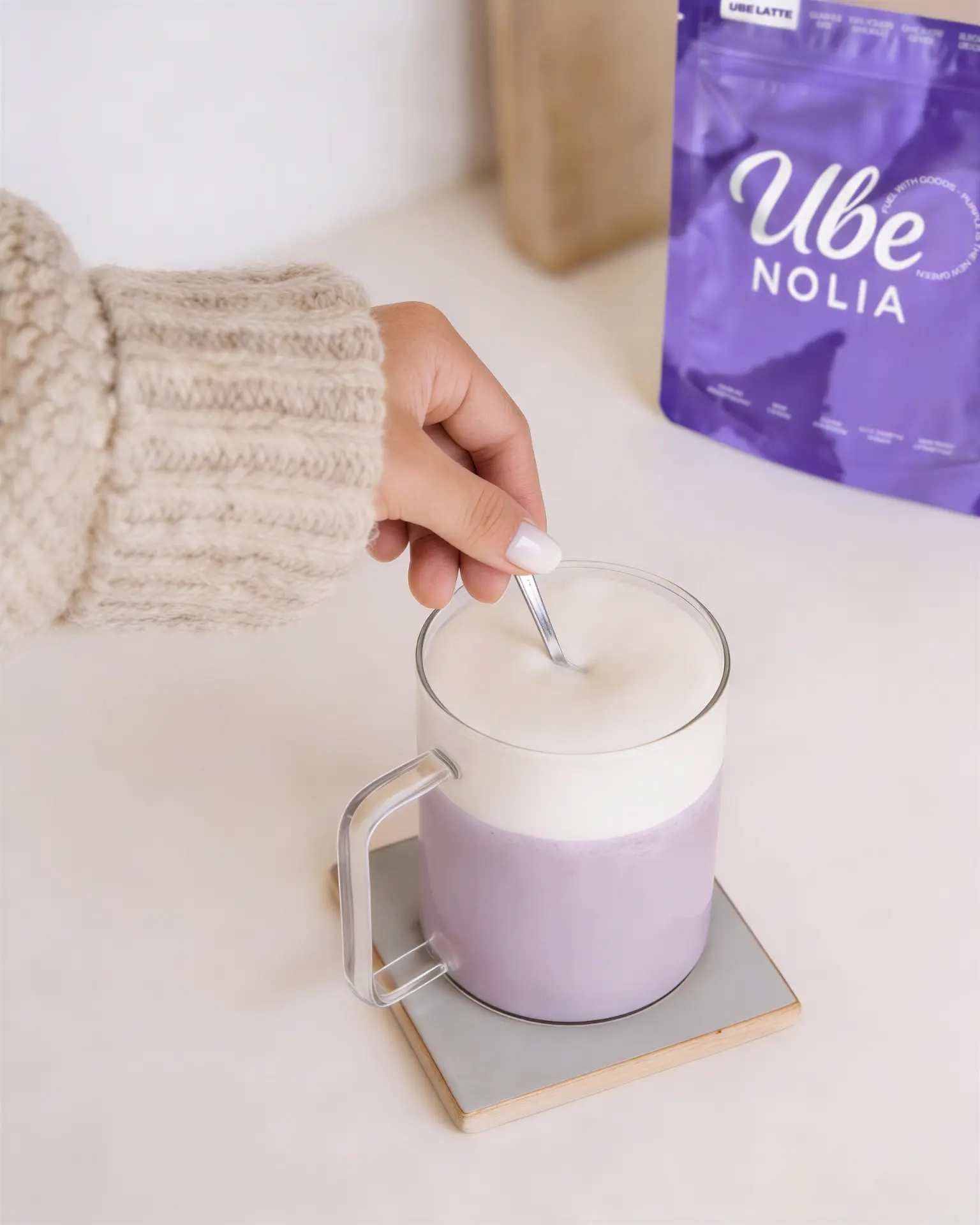 Ube Nolia ube latte being stirred next to the ube powder pouch