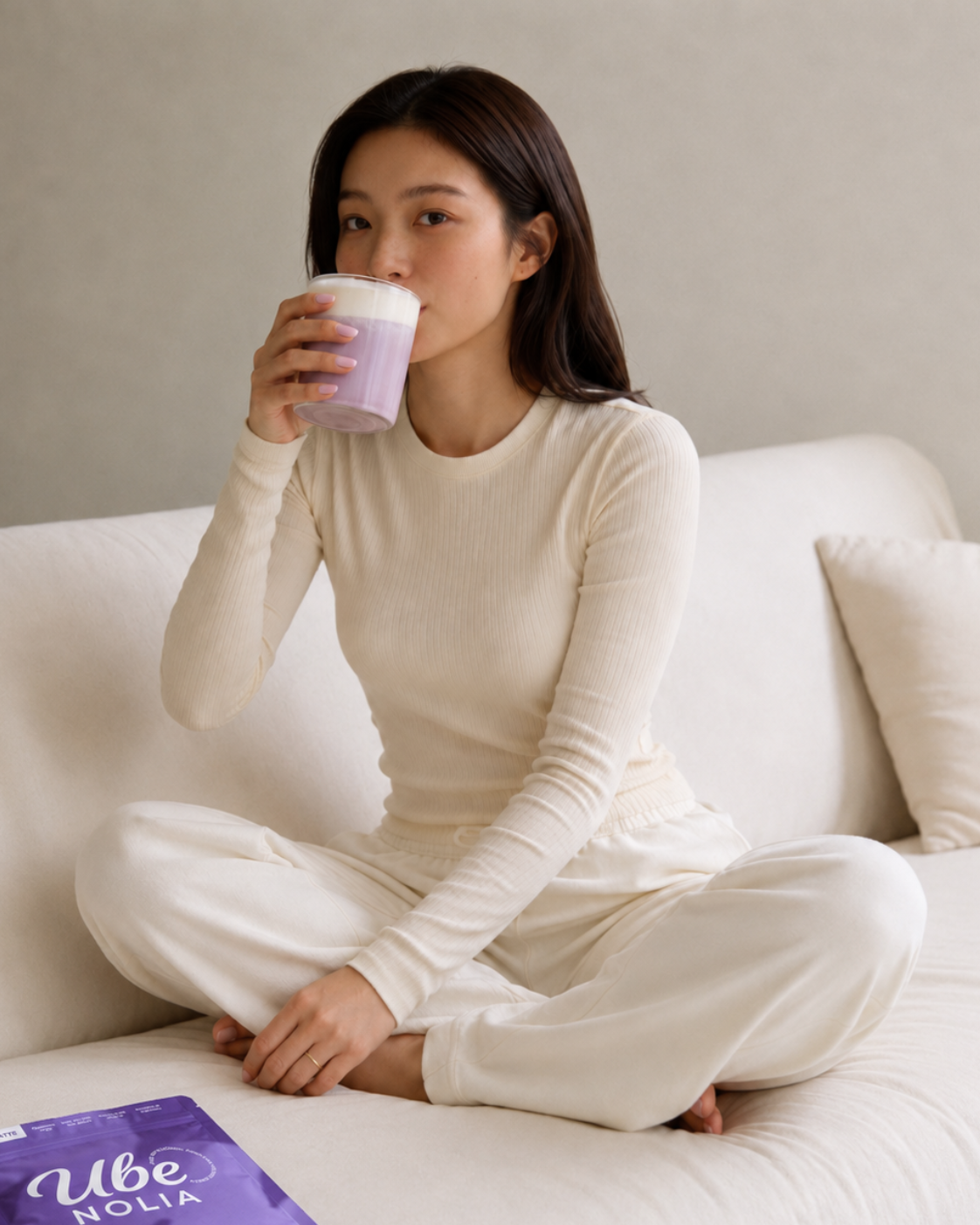 Woman drinking an Ube Nolia ube latte next to the ube powder pouch