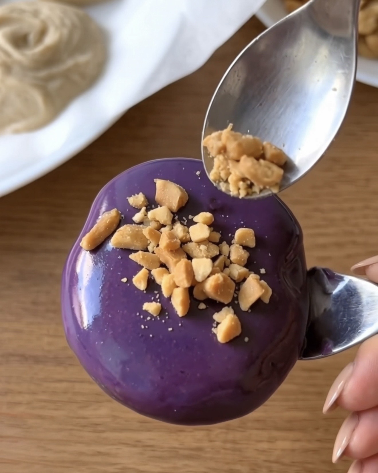 Arachides grillées concassées parsemées sur une bouchée glacée au yogourt Ube Nolia recouverte de chocolat blanc ube violet