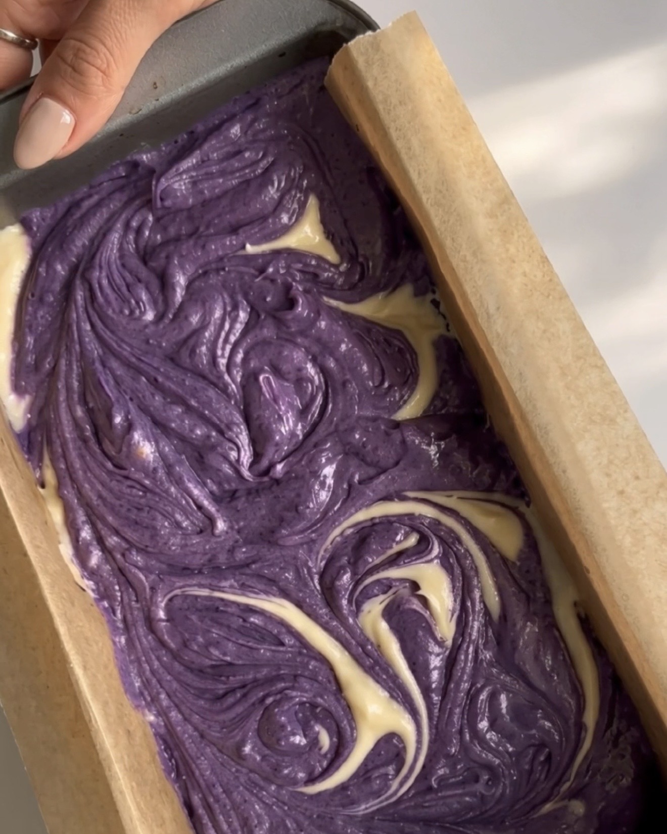 Pâtes violette et vanille mélangées en un motif marbré dans le moule à cake pour le cake marbré ube Ube Nolia