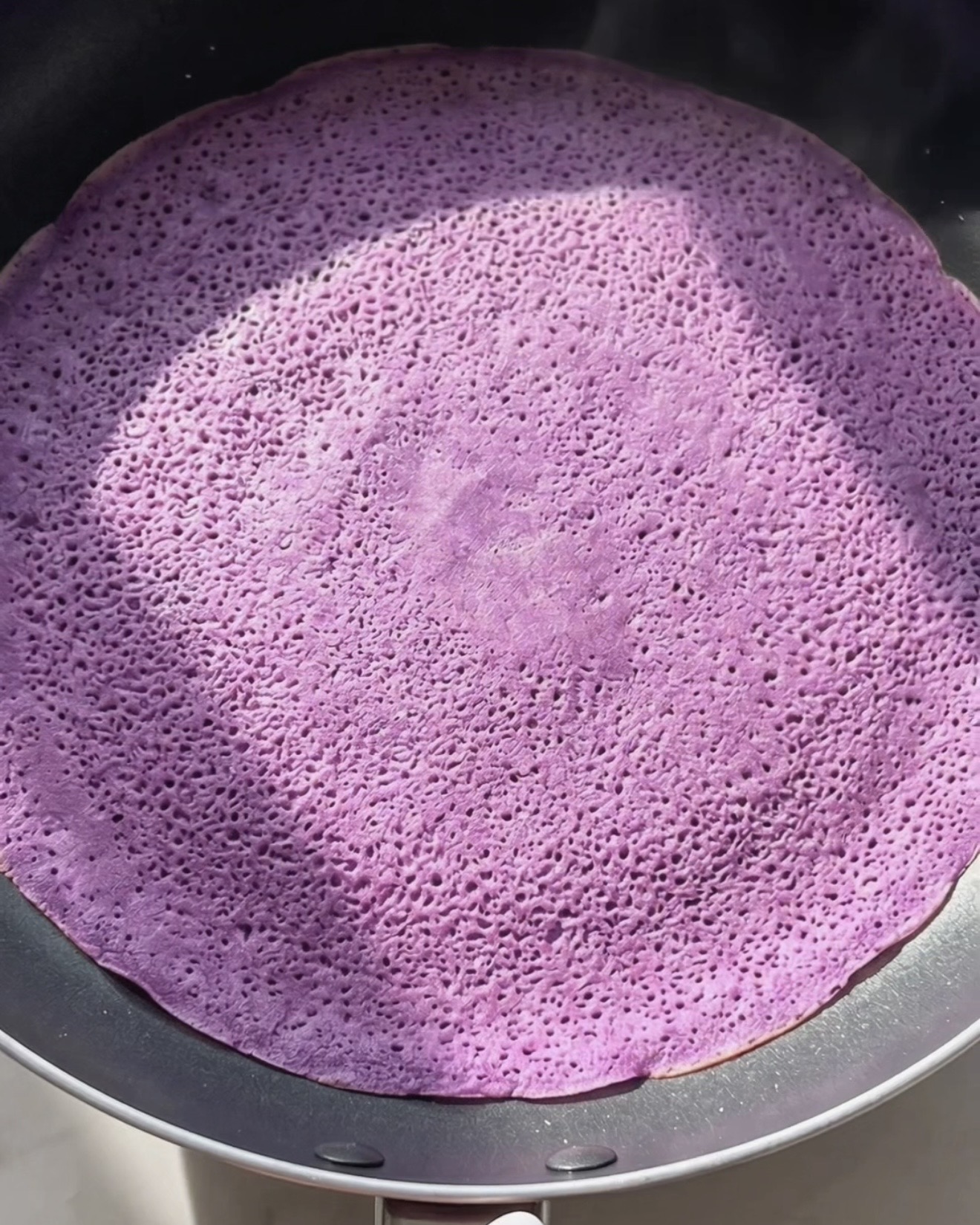 Cuisson d'une fine crêpe ube dadar gulung violette dans une poêle antiadhésive