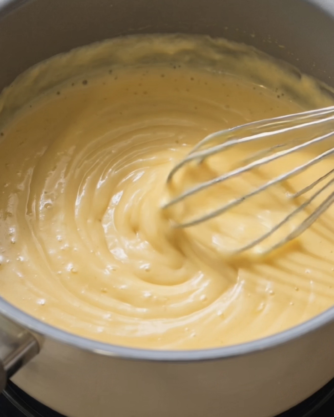Lait de coco et lait concentré réchauffés ensemble pour faire la base de la garniture ube halaya pour l'ube dadar gulung
