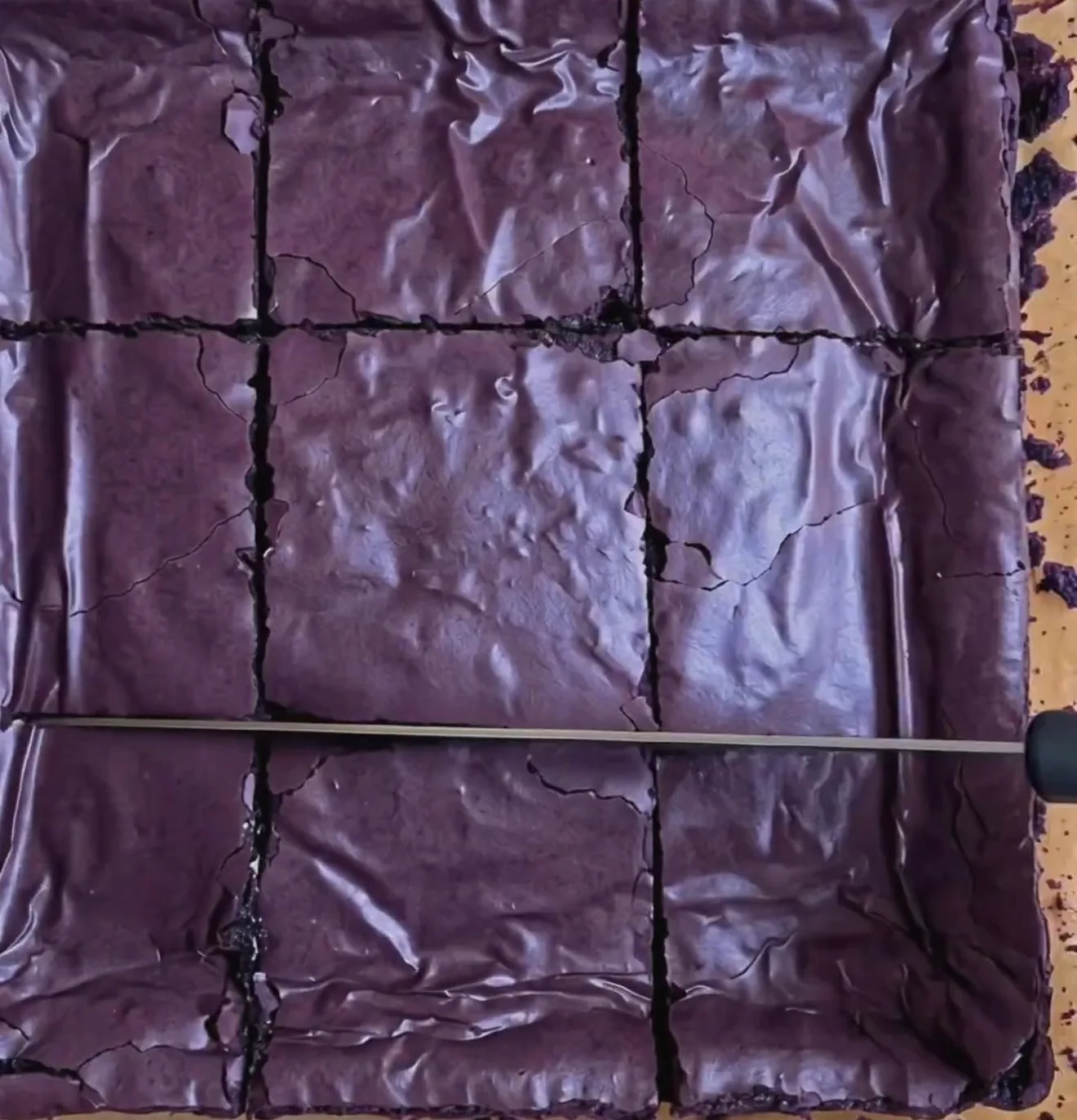 Brownies ube fondants cuits avec un dessus craquant violet foncé brillant, coupés en 9 carrés avec de l'UBE NOLIA® powder