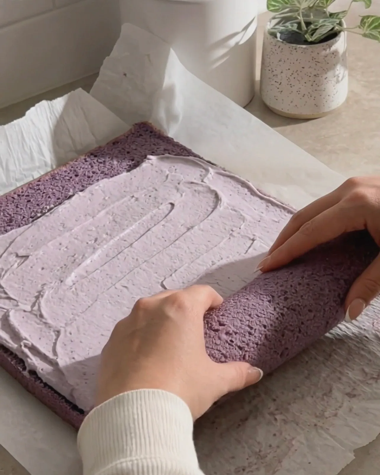 Étaler la crème fouettée à l'ube sur le gâteau chiffon violet et le rouler par Ube Nolia