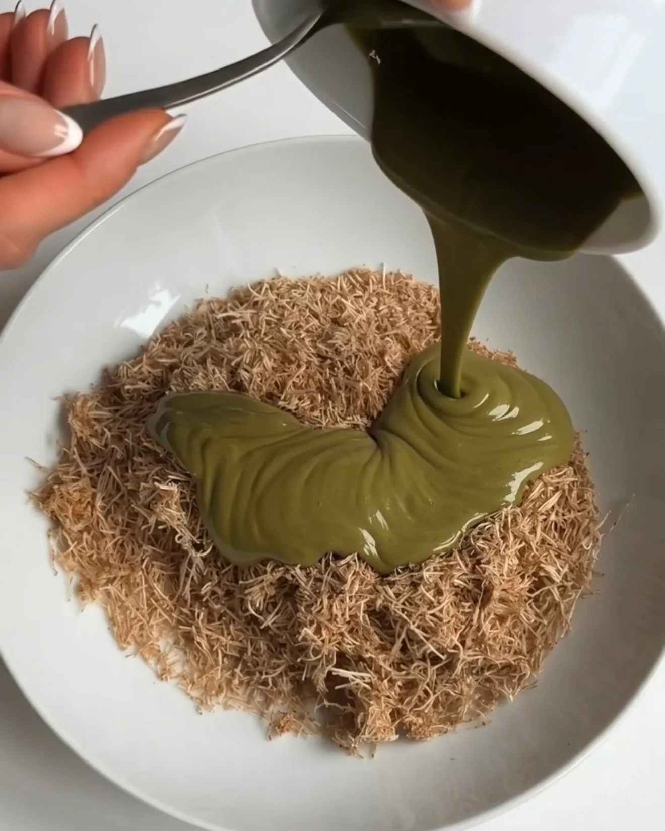 Crème de pistache versée sur un bol de pâte à kataifi grillée pour la garniture des barres de brownie au chocolat Ube Dubai par Ube Nolia