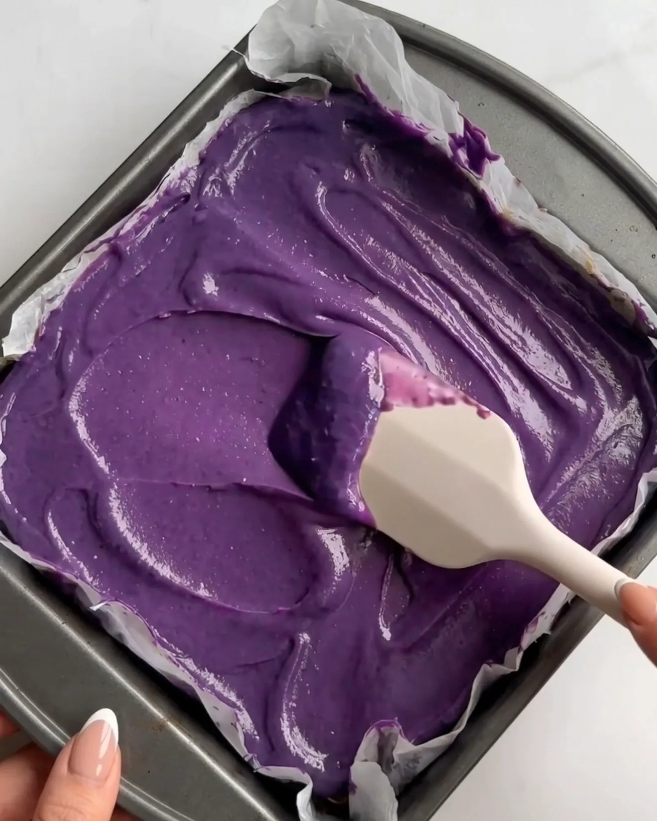 Ganache au chocolat blanc ube violette vive étalée sur la couche de pistache kataifi pour les barres de brownie au chocolat Ube Dubai par Ube Nolia